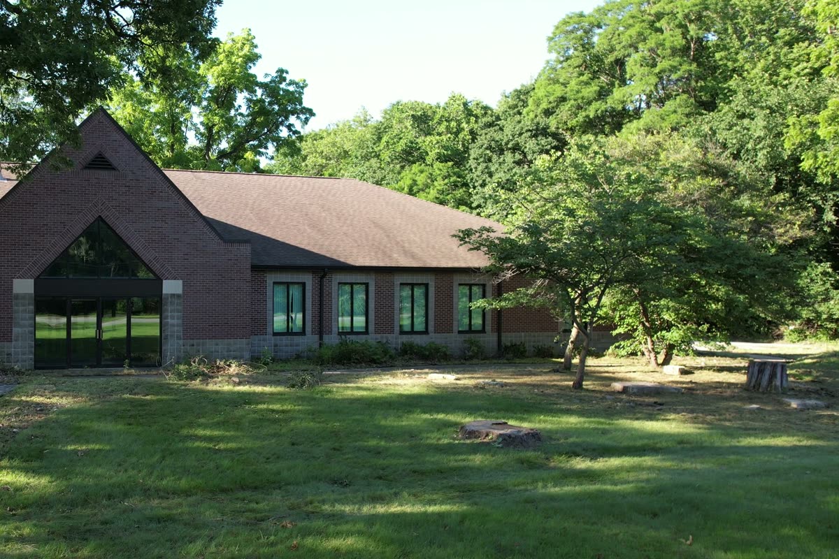 The brick office building behind its lawn, with the gabled glass entrance in the middle.