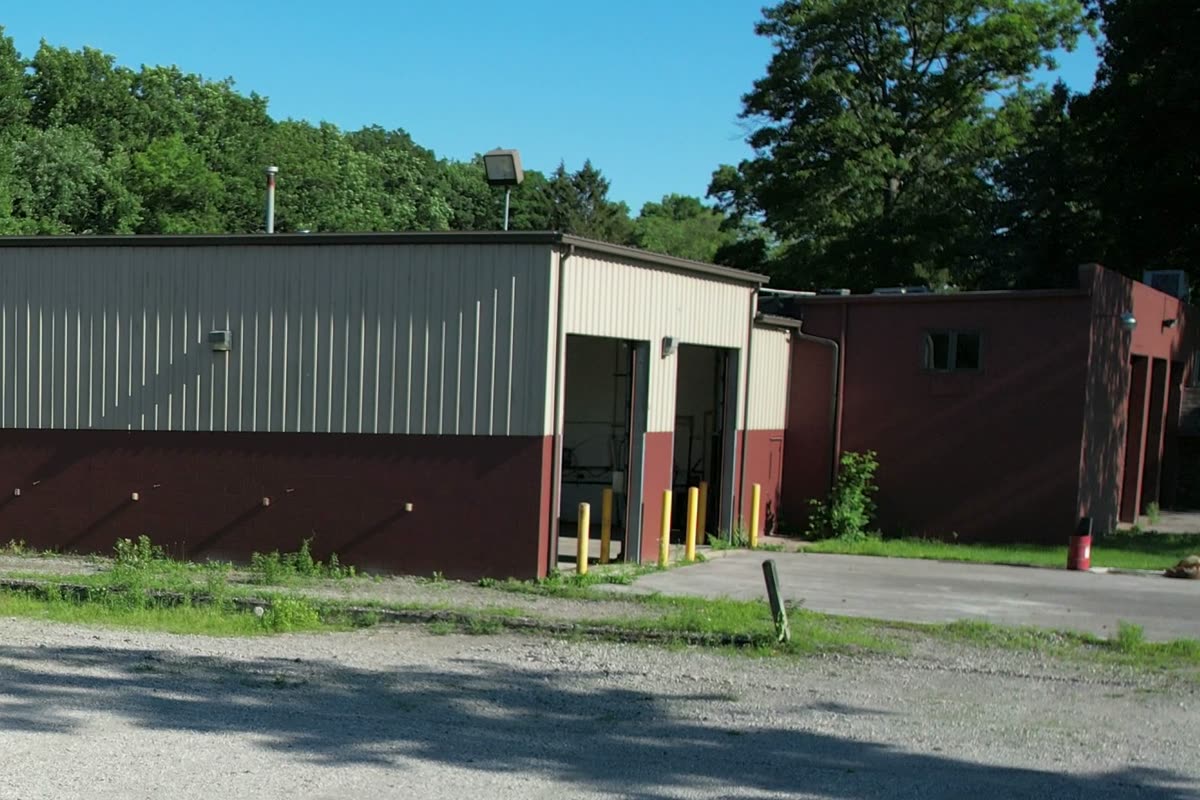The maintenance shop from the yard, with two drive-in doors open on the gable end.