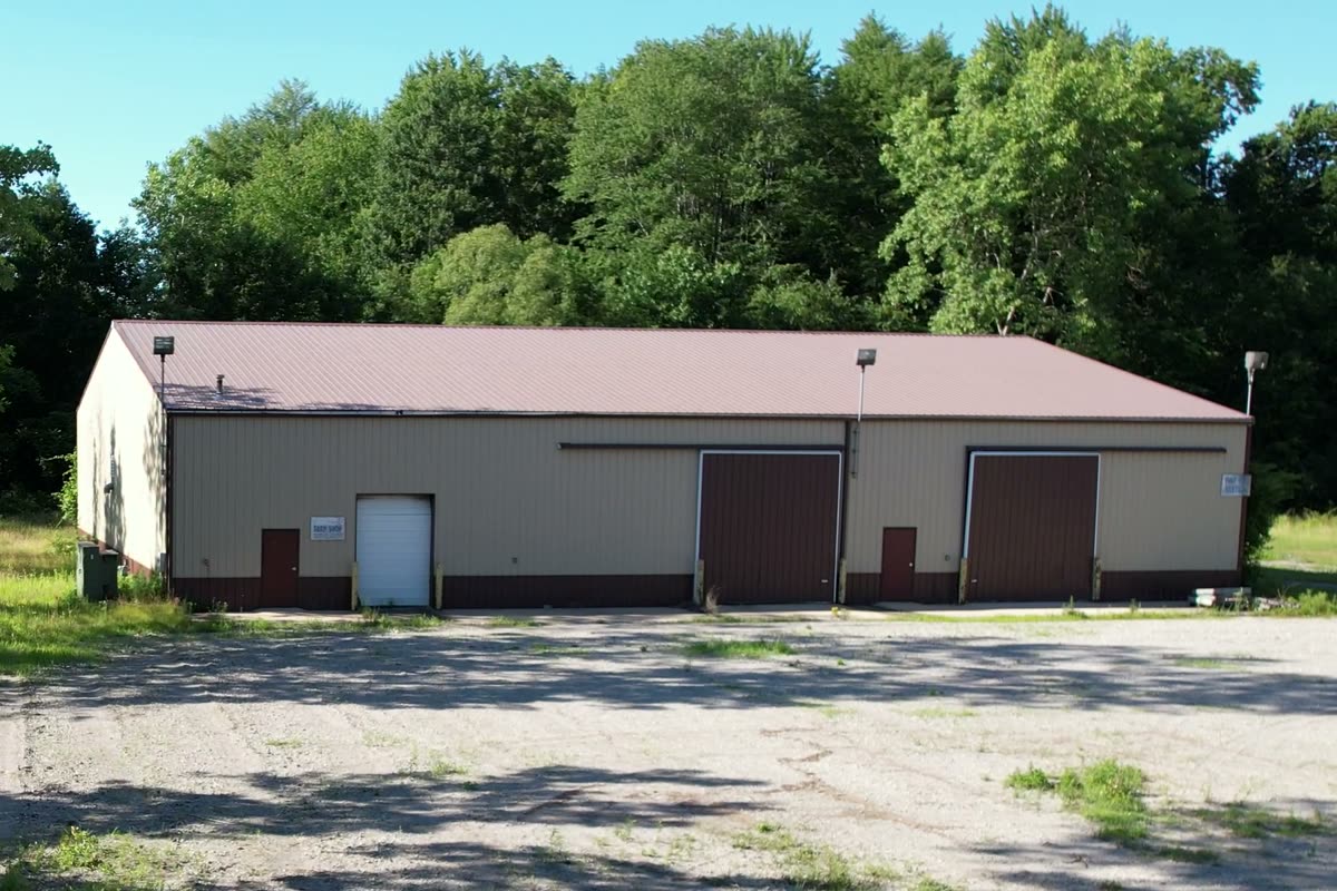 The tarp repair and storage building at the rear of the site, with its overhead doors facing the yard.